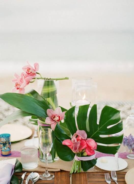 the table is set with pink flowers and greenery