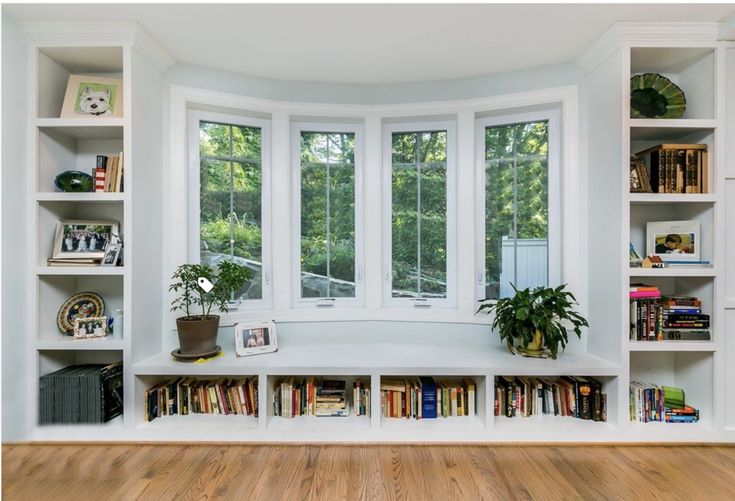 an empty room with bookshelves and plants on the windowsills in it