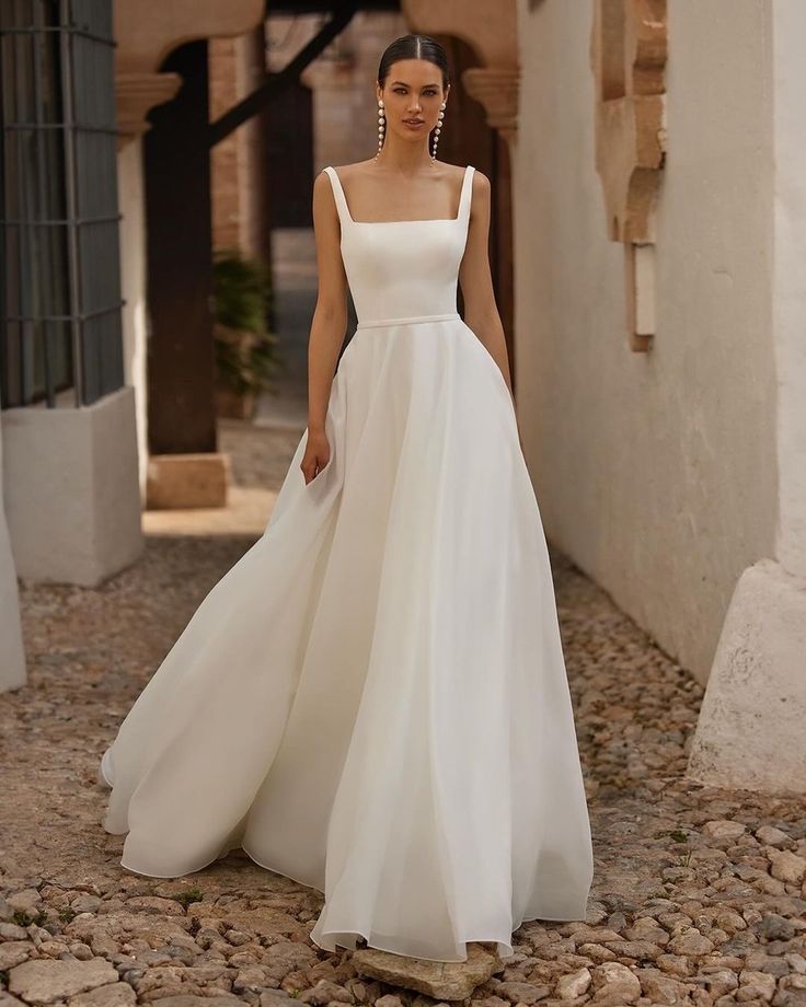 a woman in a white dress is walking down the street