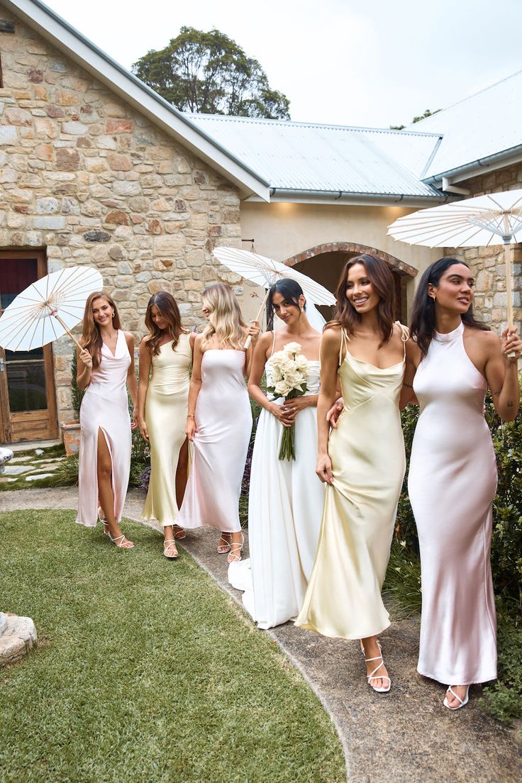 the bridesmaids are walking down the path with their umbrellas in front of them