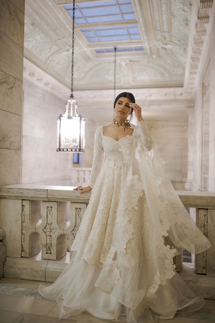 a woman in a wedding dress standing on a balcony with her arms behind her head