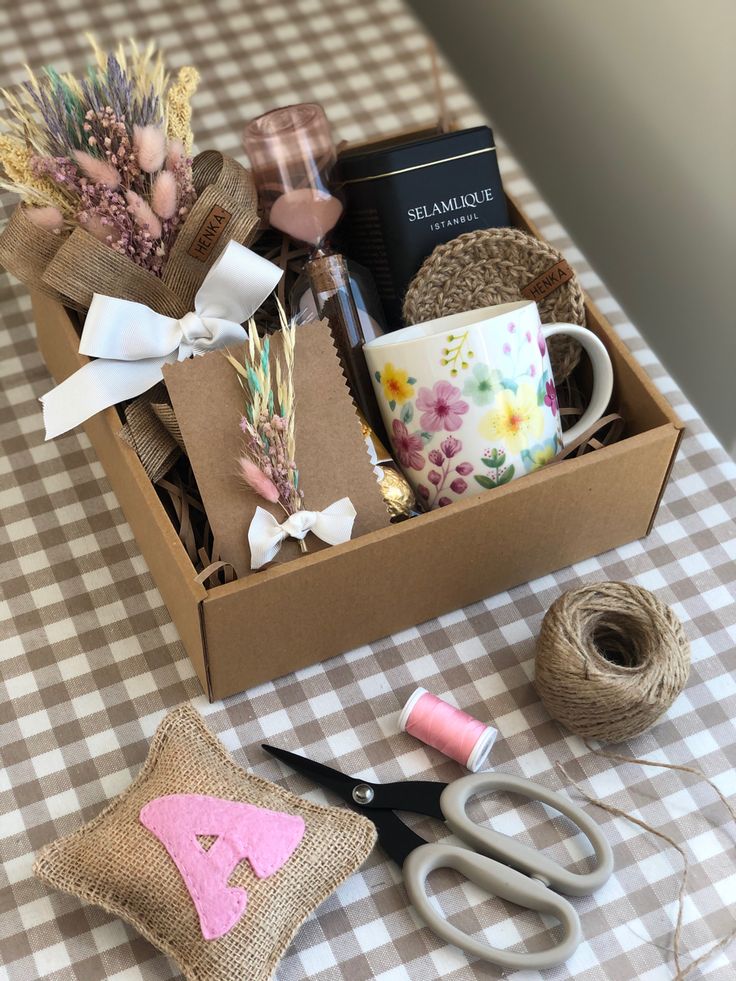 a box with scissors, yarn and other crafting supplies on a checkered table cloth