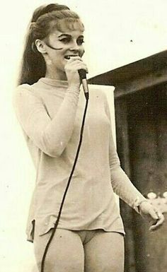 an old photo of a woman in tights singing into a microphone and holding her hand up to her mouth