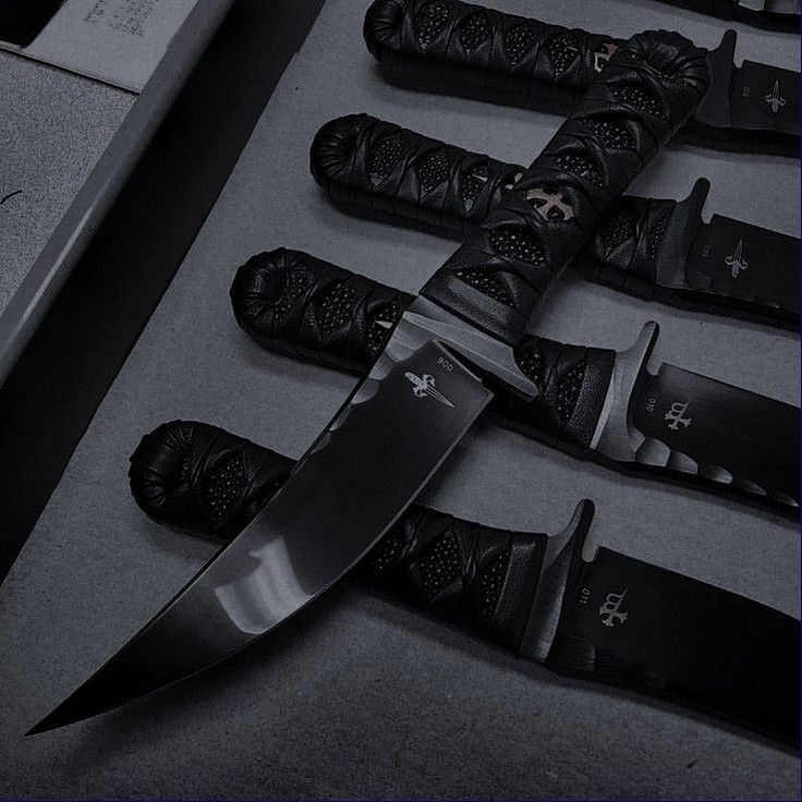 several knives are lined up on the floor next to each other, with black leather handles