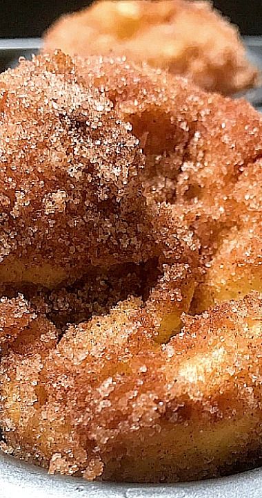 two sugared donuts sitting on top of a metal tray next to each other