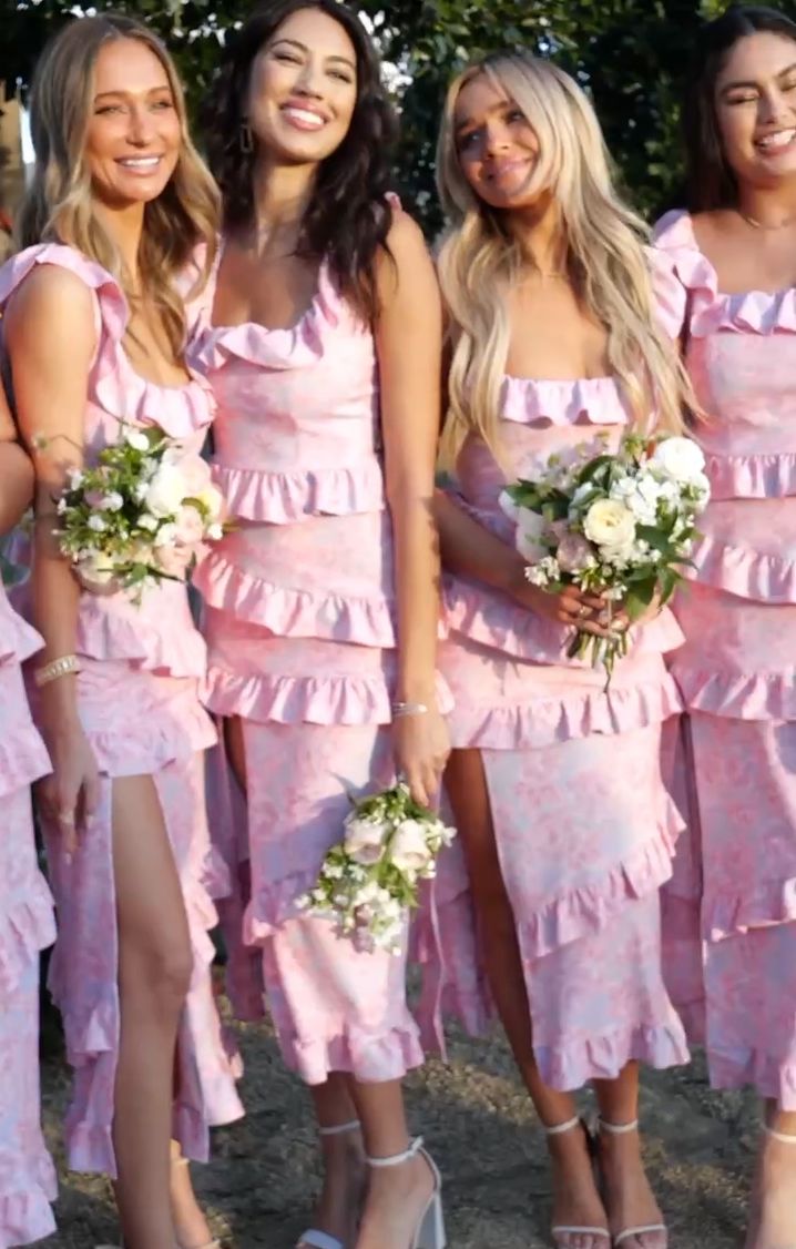 a group of women standing next to each other wearing pink dresses and holding bouquets