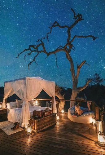 a bed sitting on top of a wooden floor under a night sky