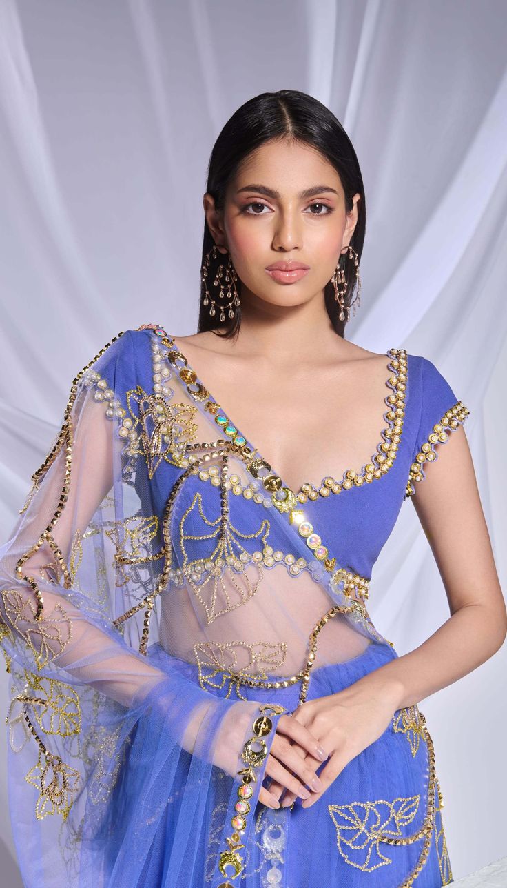 Crafted with meticulous detailing, this deep blue organza sari is richly adorned with metallic accents, crystals, and sequins forming floral patterns while the pre-stitched tulle bottom features delicate scattered embroidery. Complementing the ensemble, the blue georgette blouse is detailed with metal circles, pearls embroidery, and intricate cutwork. Embellished Chanderi Pre-draped Saree, Festive Blue Wedding Pre-draped Saree, Blue Organza Pre-draped Saree With Dupatta, Festive Organza Blouse Piece With Mirror Work, Festive Organza Blouse With Dupatta, Blue Tissue Silk Pre-draped Designer Saree, Designer Blue Tissue Silk Pre-draped Saree, Blue Tissue Silk Pre-draped Saree For Designer Wear, Organza Saree With Mirror Work For Reception