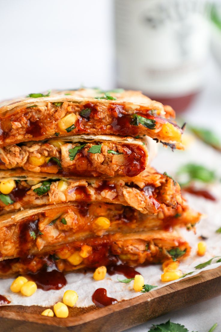 a stack of mexican chicken quesadillas on a wooden platter with garnishes