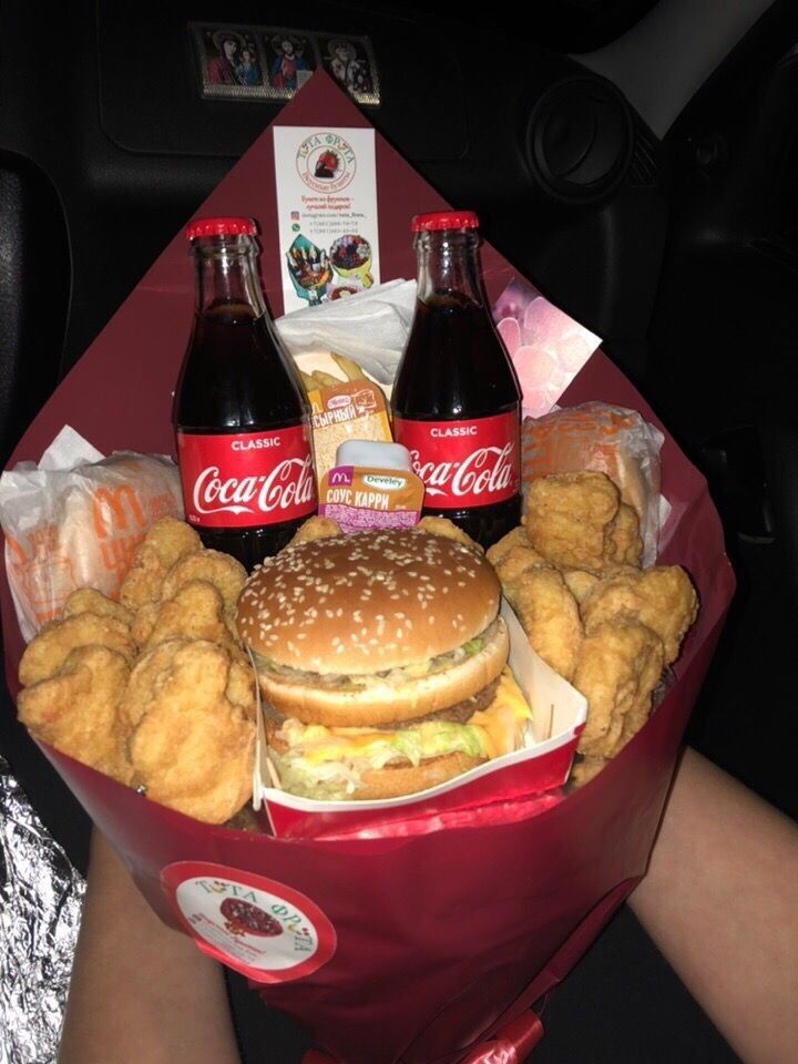 a basket filled with lots of food next to two sodas and some fried chicken