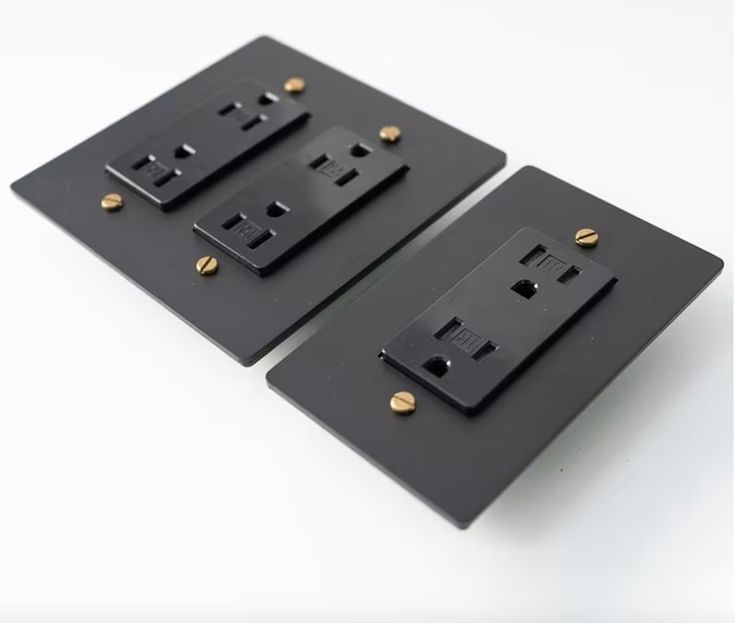 two black electrical outlet covers with gold studs on each one and the other side