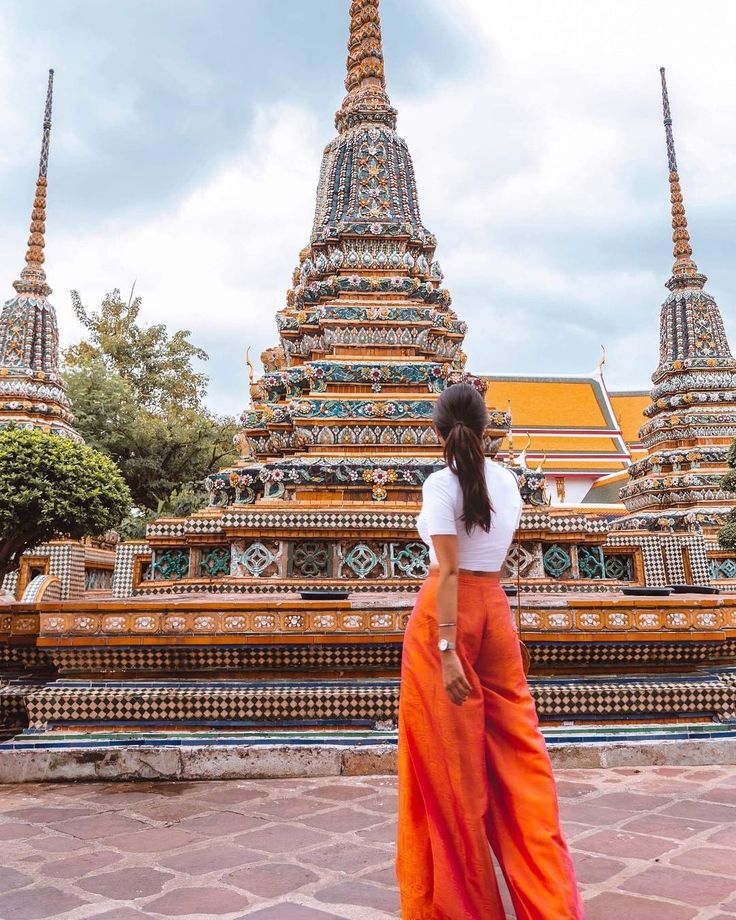 a woman standing in front of a large building with many spires on it's sides