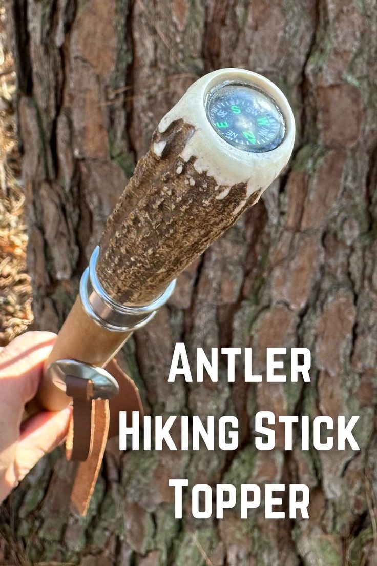 a person holding a stick in front of a tree with the words antler hiking stick topper on it