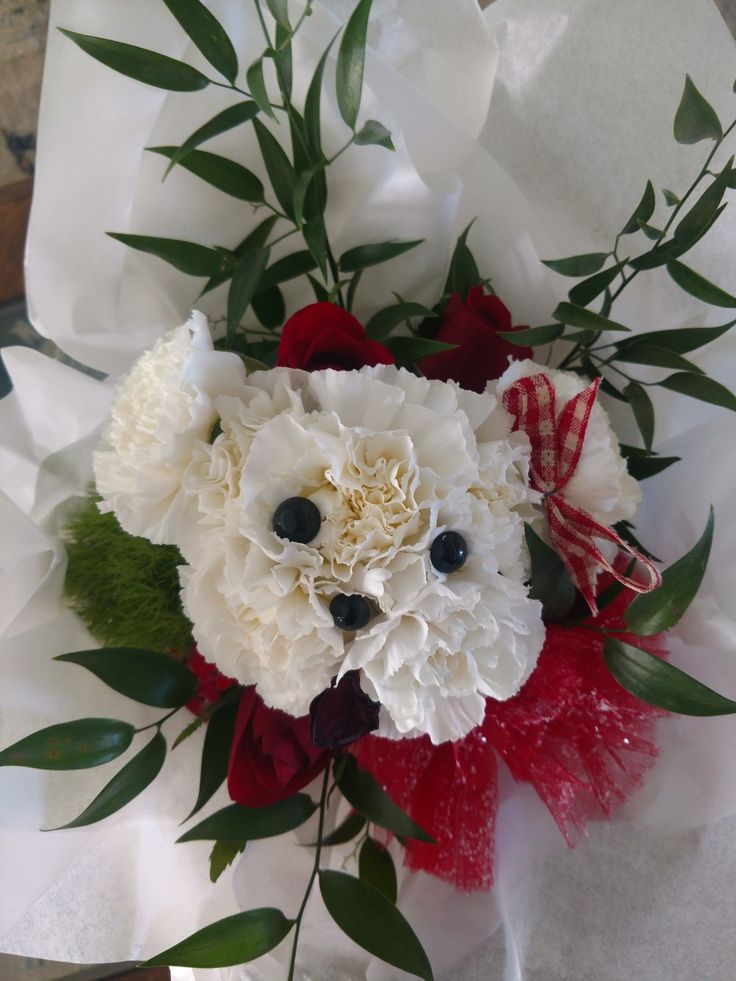 a bouquet with white and red flowers in it's center, on top of tissue paper