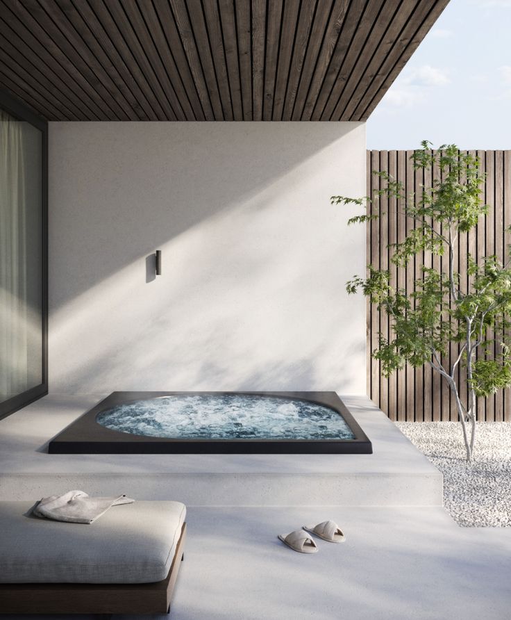 an outdoor jacuzzi tub in the middle of a patio with a small tree