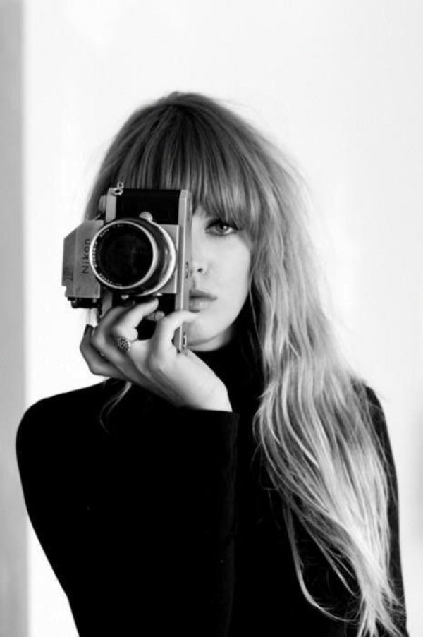 black and white photograph of a woman taking a photo with an old fashioned film camera