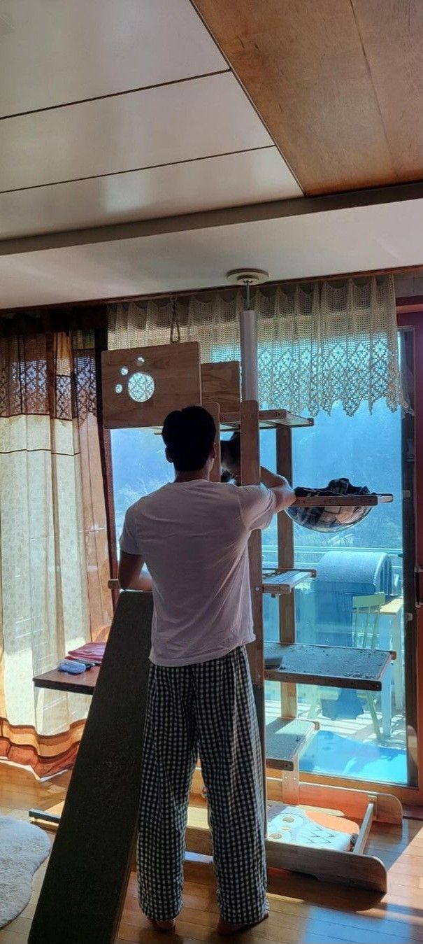 a man standing on top of a wooden floor next to a window covered in curtains