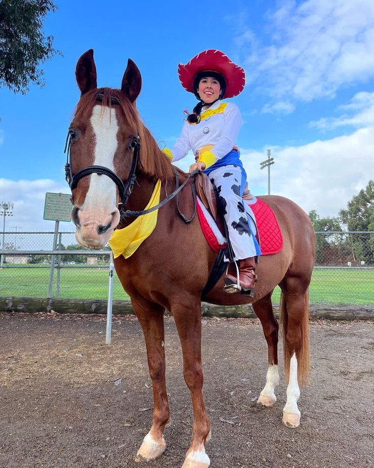 a woman riding on the back of a brown horse wearing a red and yellow hat