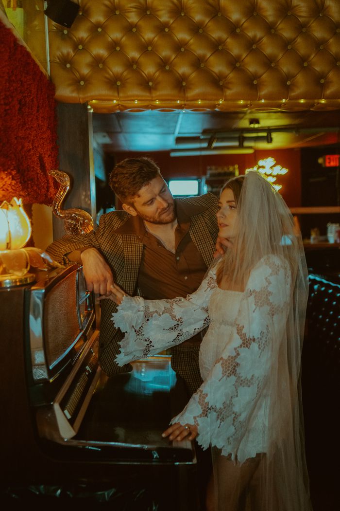 a man and woman standing next to each other in front of a tv set with candles on it