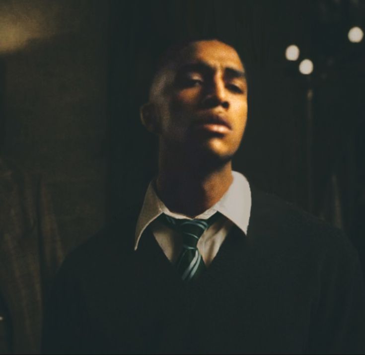 a man wearing a sweater and tie in the dark