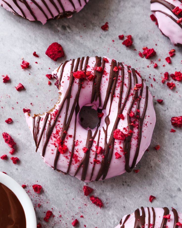 chocolate covered donuts with pink frosting and sprinkles on a table