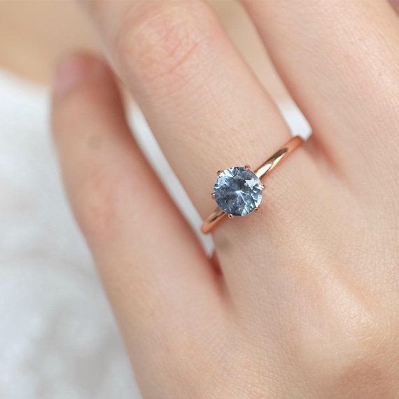 a woman's hand with a ring on it and a blue stone in the middle