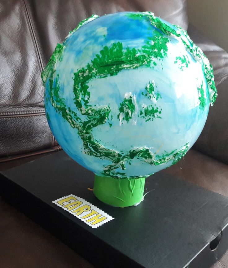 a blue and green globe sitting on top of a black table next to a brown leather couch