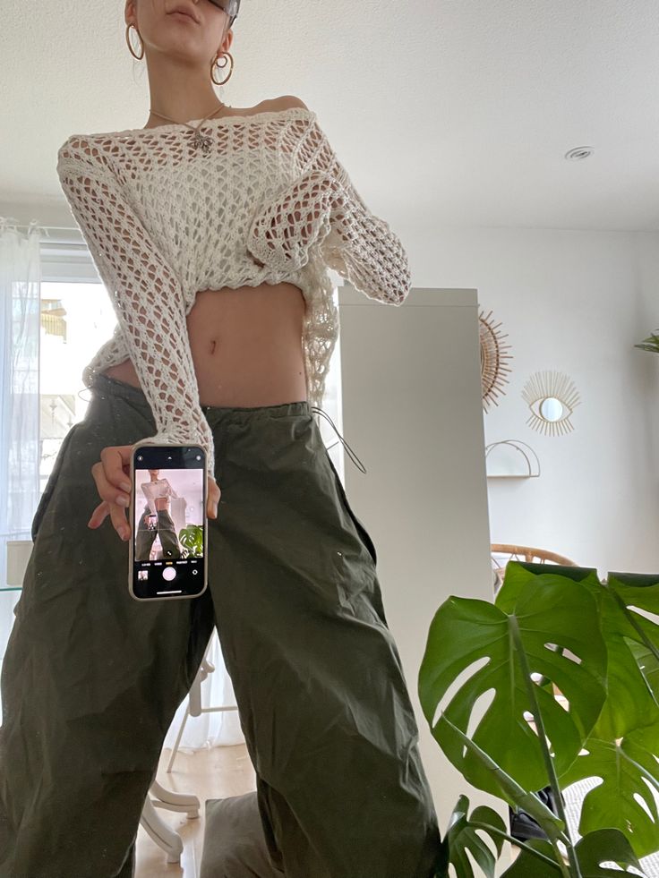 a woman is taking a selfie with her cell phone while standing in front of a plant