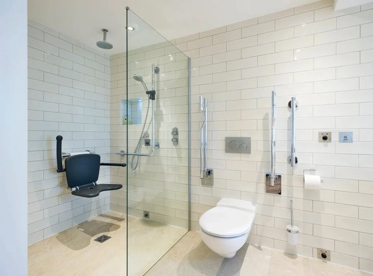 a white toilet sitting next to a shower in a bathroom with glass walls and doors