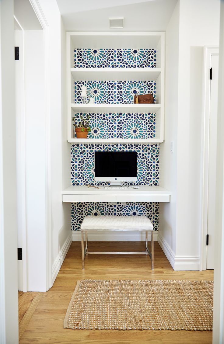 a white desk with a computer on top of it in front of a blue and white wall