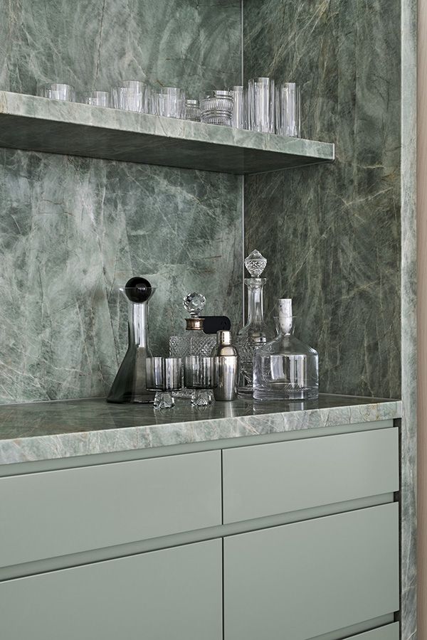 an image of a kitchen counter with glasses and bottles on the top shelf in front of it