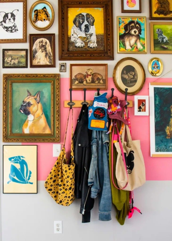 there are many pictures on the wall and purses hanging from hooks in front of them