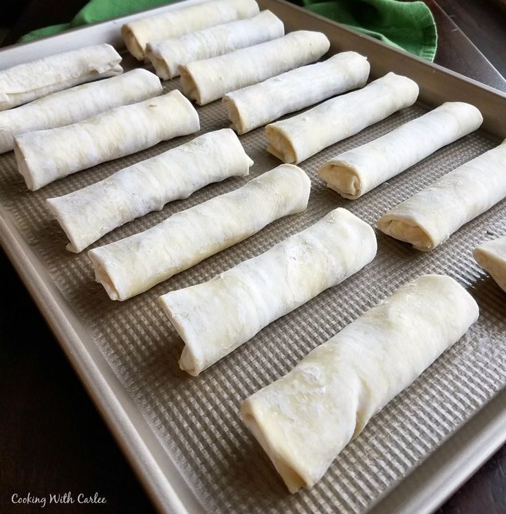 several rolled up food items sitting on a baking sheet ready to go into the oven