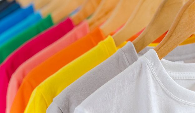 a row of colorful shirts hanging on a clothes line with wooden hangers in the foreground