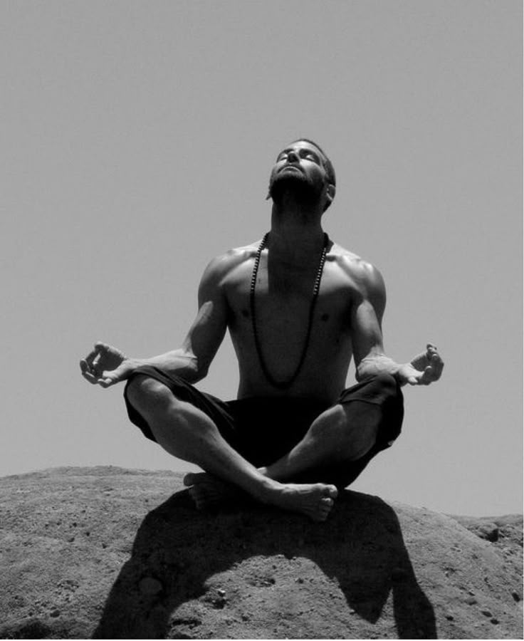 a man sitting on top of a rock doing yoga