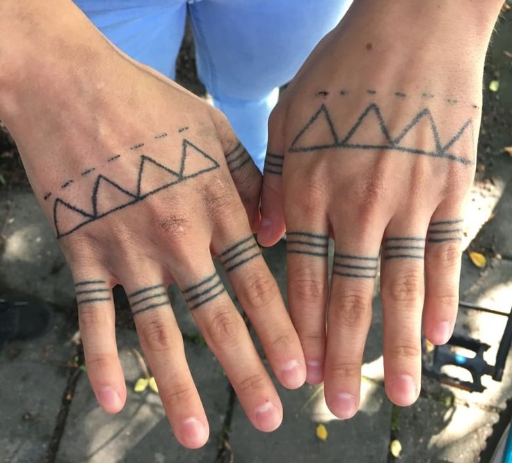 two people with matching tattoos on their hands, one holding the other's hand