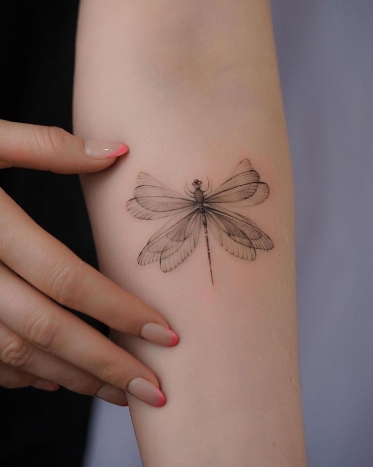 a woman's arm with a dragonfly tattoo on it