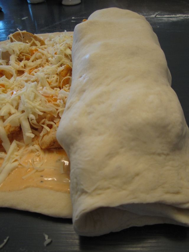 an uncooked pizza sitting on top of a table next to a roll of dough