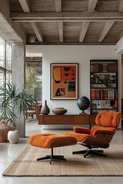 an orange chair and ottoman in a modern living room with large windows, bookshelves and artwork on the wall