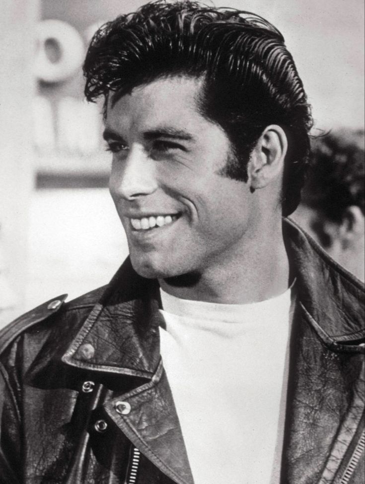 a black and white photo of a man in a leather jacket smiling at the camera