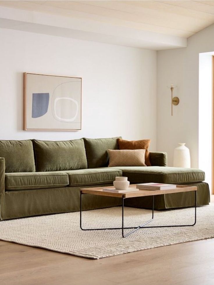 a living room with a green couch and coffee table in front of a painting on the wall