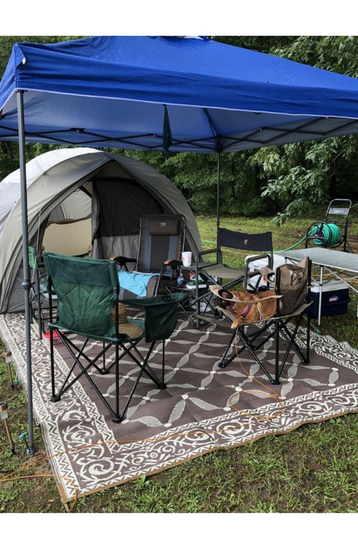 a tent set up in the middle of a field with chairs and tables under it