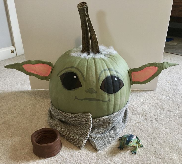 a stuffed toy is sitting on the floor next to a pumpkin