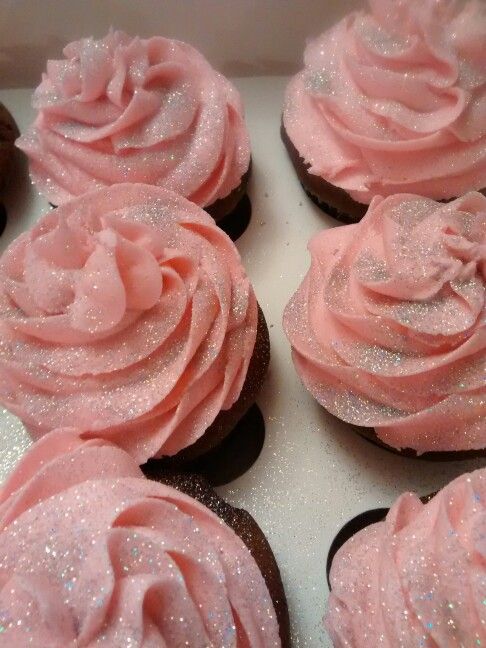 cupcakes with pink frosting and sprinkles in a box