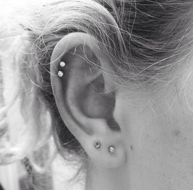 black and white photograph of a woman's ear with two piercings on it