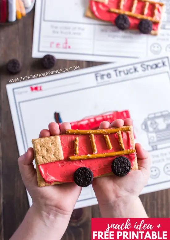 a person holding up a piece of food with raspberries on it and chocolate chips in the shape of a firetruck