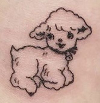 a small black and white dog tattoo on the back of a woman's stomach