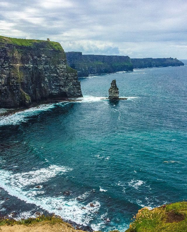 a boat is out in the ocean near cliffs and water with green grass on either side