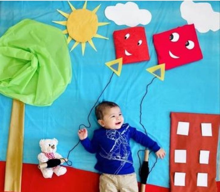 a young boy standing in front of a bulletin board with paper cutouts on it