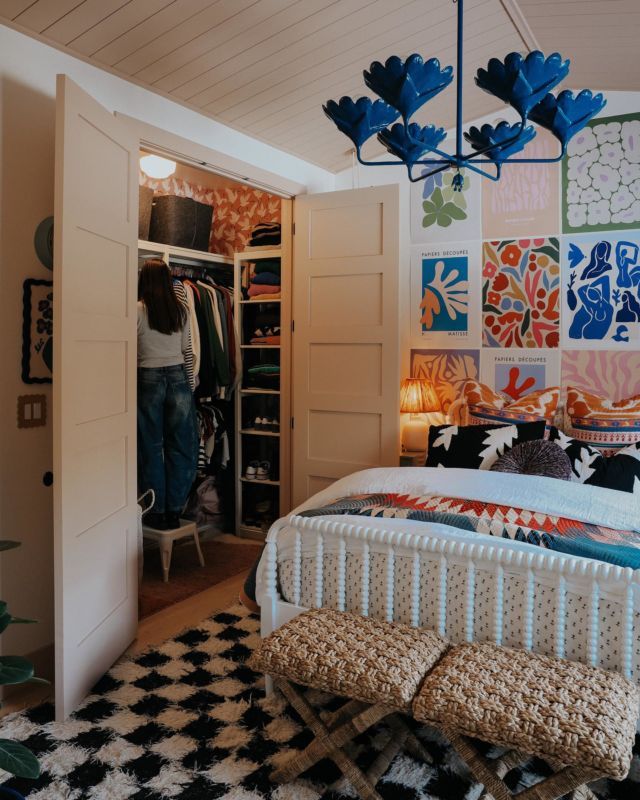 a bedroom with an open closet next to a bed and a checkered rug on the floor